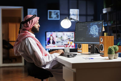 Rear view of woman using digital tablet in office