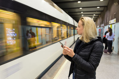 Woman using mobile phone while standing on train