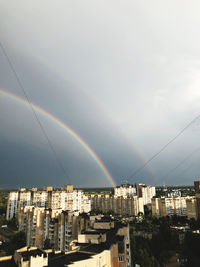 Rainbow over buildings in city against sky