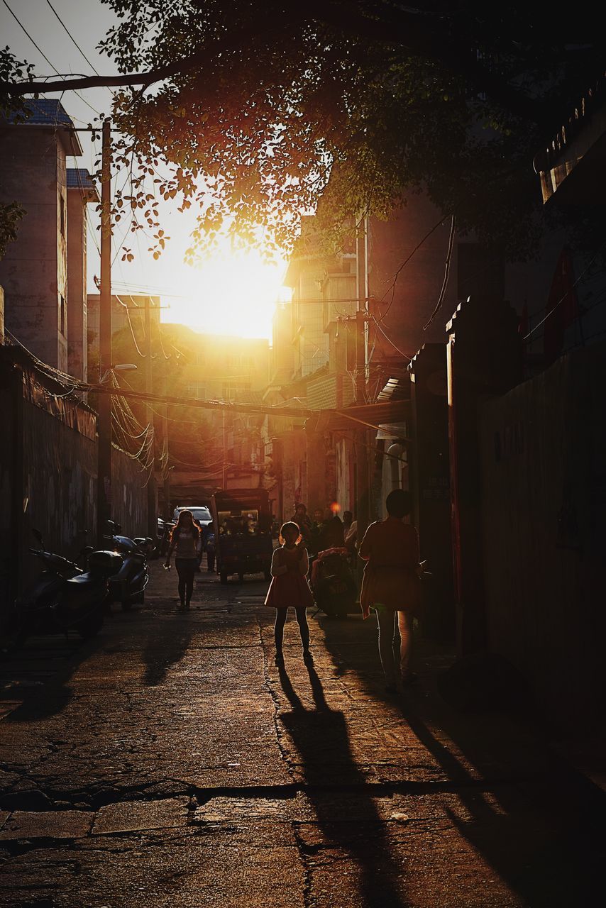 street, building exterior, transportation, men, city, walking, lifestyles, architecture, built structure, sunlight, city life, leisure activity, bicycle, land vehicle, road, person, shadow, sidewalk, mode of transport