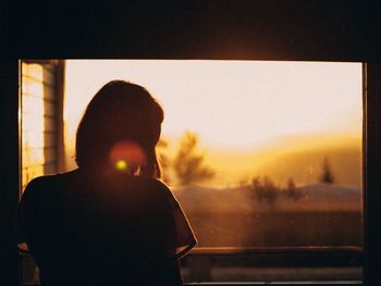 Rear view of woman looking through window