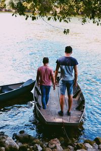 Rear view of men standing on boat sailing in river