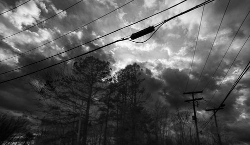 Low angle view of electricity pylon against cloudy sky