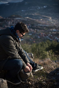 Full length of man sitting on cliff