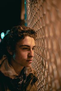 Close-up of young woman looking through fence