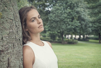 Portrait of young woman standing against trees