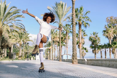 Full length portrait of young woman roller skating on footpath