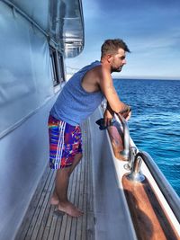 Young man on boat in sea against sky