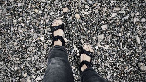 Low section of person walking on stone covered ground