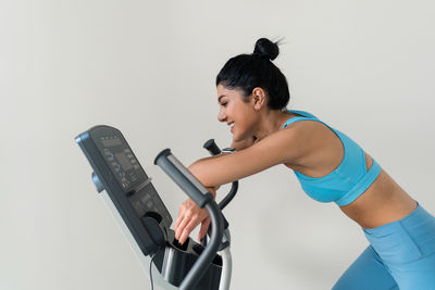 Young woman training at the gym using eliptical crosstrainer