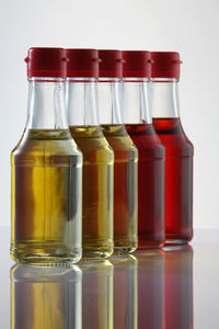 Palm oil, sesame seed oil, olive oil, grape seed oil and corn oil in glass bottle over white 