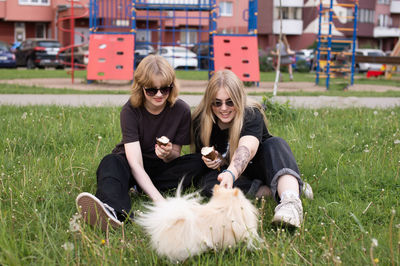 Two funny girls are eating ice cream and playing with a pomeranian dog. holidays