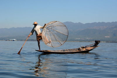 People fishing in sea against clear sky