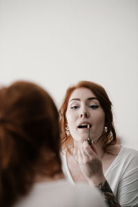 Young woman applying make-up at home