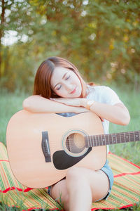 Young woman with guitar on grassy field at park