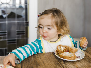 Close-up of cute girl eating food on table at home