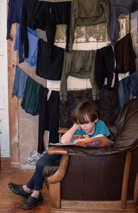 Full length of kid sitting and browsing mobile phone