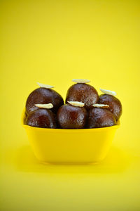 Close-up of chocolate in bowl against yellow background