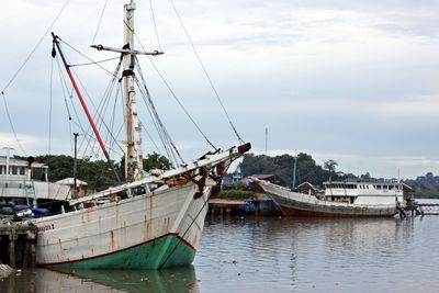 Boats moored at harbor against sky