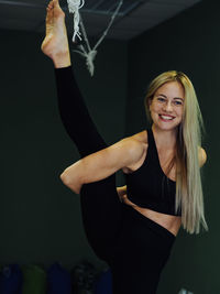Portrait of young woman standing against black background