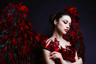 Portrait of young woman against black background