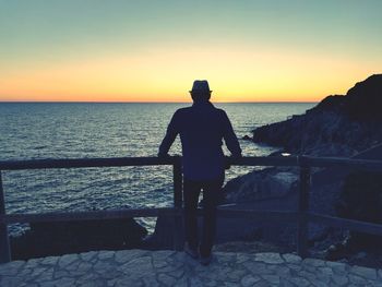 Silhouette man standing on beach against clear sky during sunset