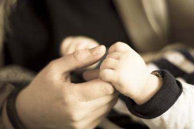 Close-up of mother holding child hand