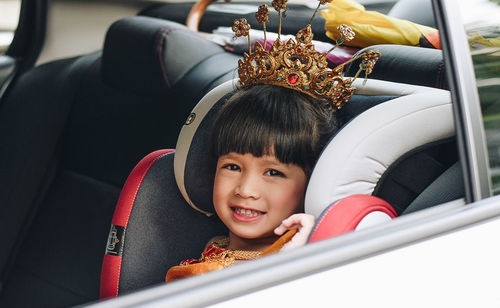 Portrait of smiling girl wearing crown while sitting in car