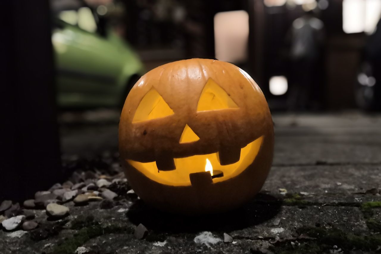 CLOSE-UP OF ILLUMINATED PUMPKIN ON STONE