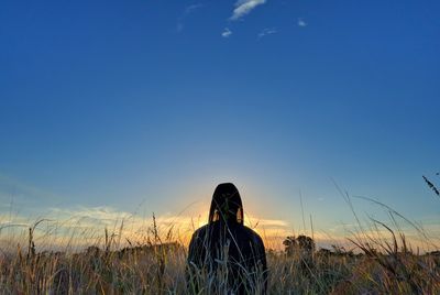 Rear view of woman standing on field against sky