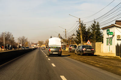 Cars on road against sky in city