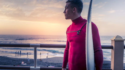 Man looking at sea against sky during sunset