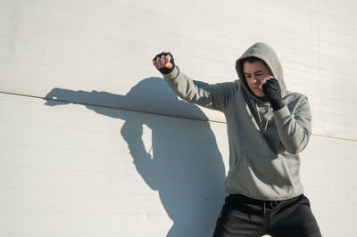 Portrait of young man standing against wall