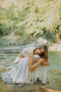 Portrait of woman sitting on rock in river