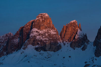 Rock formations on snowcapped mountain against sky