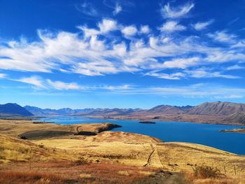 Scenic view of glacial blue lake and mountains against blue sky