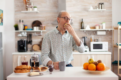 Senior man eating fruits at kitchen