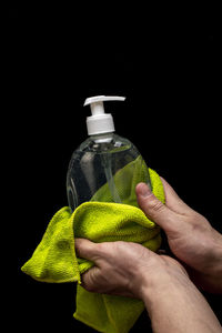 Close-up of man holding bottle against black background