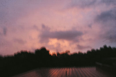 Silhouette trees on field against sky at sunset