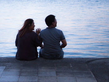 Rear view of couple sitting on shore