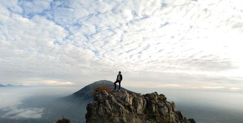 Man standing on rock against sky