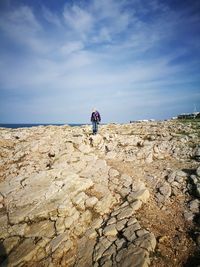 Rear view of people walking on landscape against sky