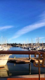 Sailboats moored on sea against blue sky