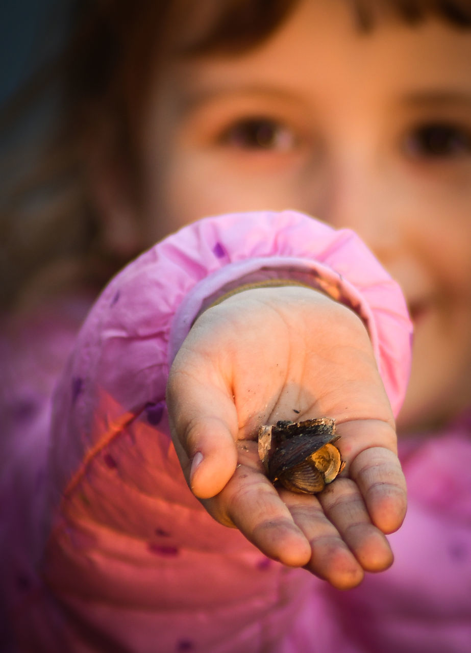 CLOSE-UP OF GIRL HOLDING PINK FLOWER OUTDOORS