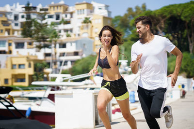 Couple running on footpath against buildings in city