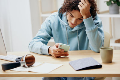 Midsection of woman using mobile phone at table