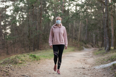 Full length of woman wearing mask walking at park