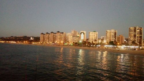 River by illuminated city against clear sky