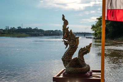 Statue by lake against sky