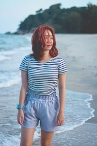 Portrait of beautiful young woman standing at beach